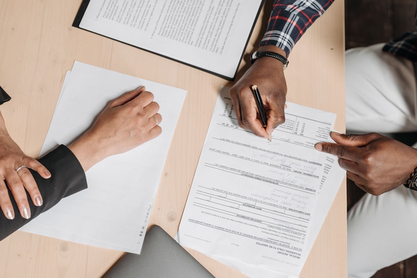 Two people reviewing and signing employment documents at a desk